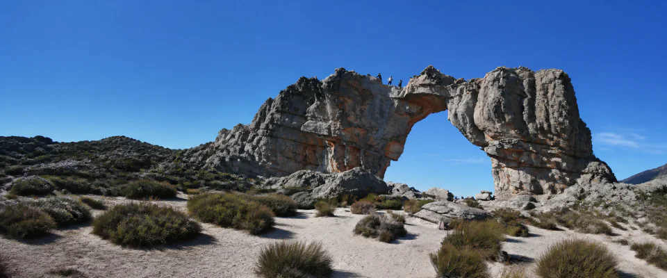 A wide view of a dramatic sandstone arch in the Cape mountains